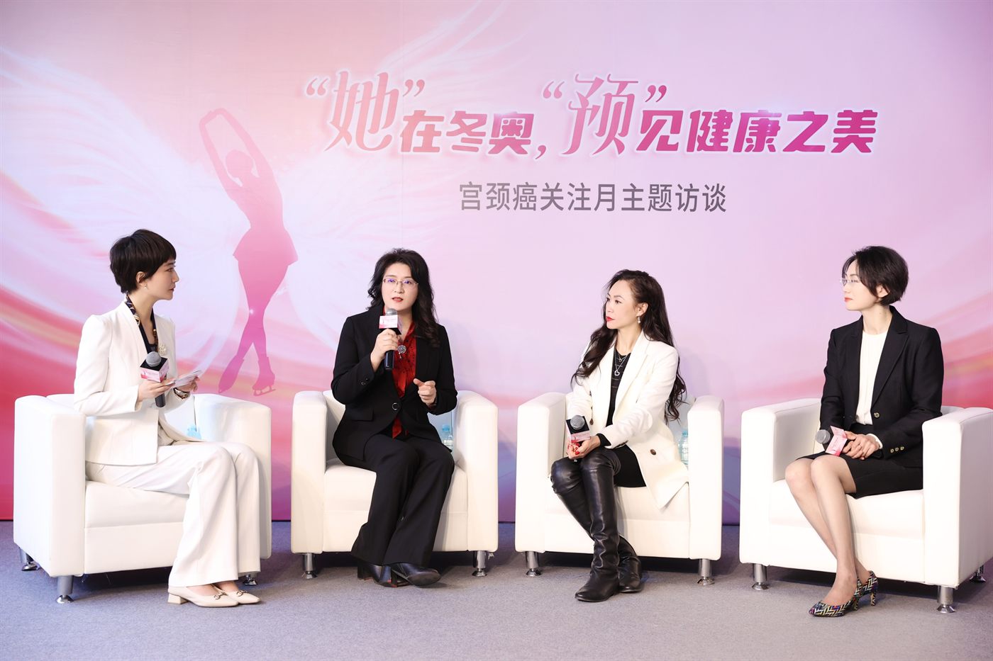 Four women in conversation on white armchairs in front of a pink backdrop carrying a figure-skater silhouette and the campaign title.